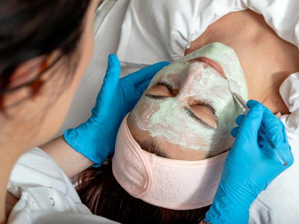 The beautician applies a collagen booster on the client's face.